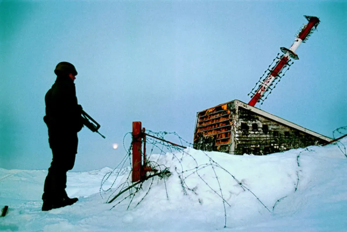 A soldier stands guard near the damaged Bjelašnica RTV tower, 1993