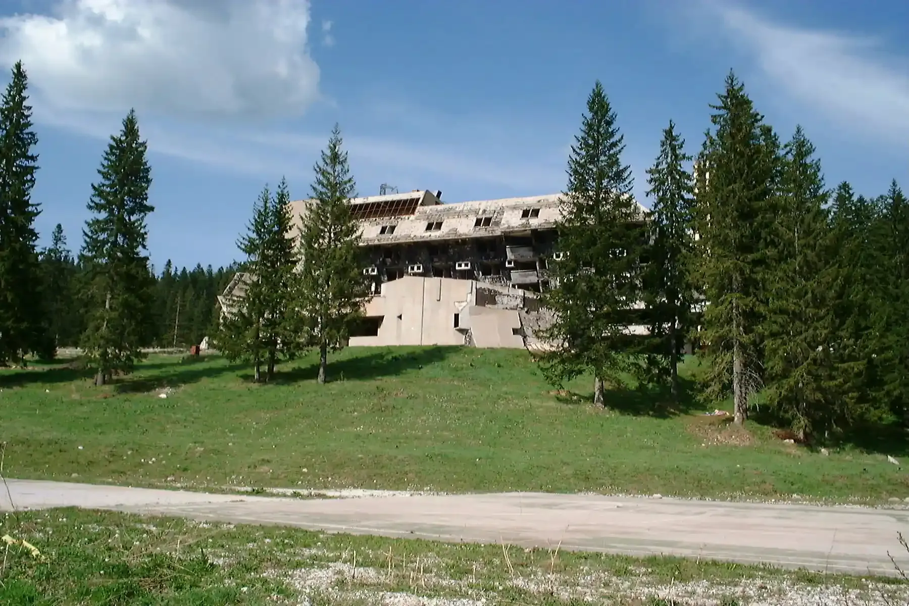 The charred remains of Hotel Igman overlook a grassy slope in 2000