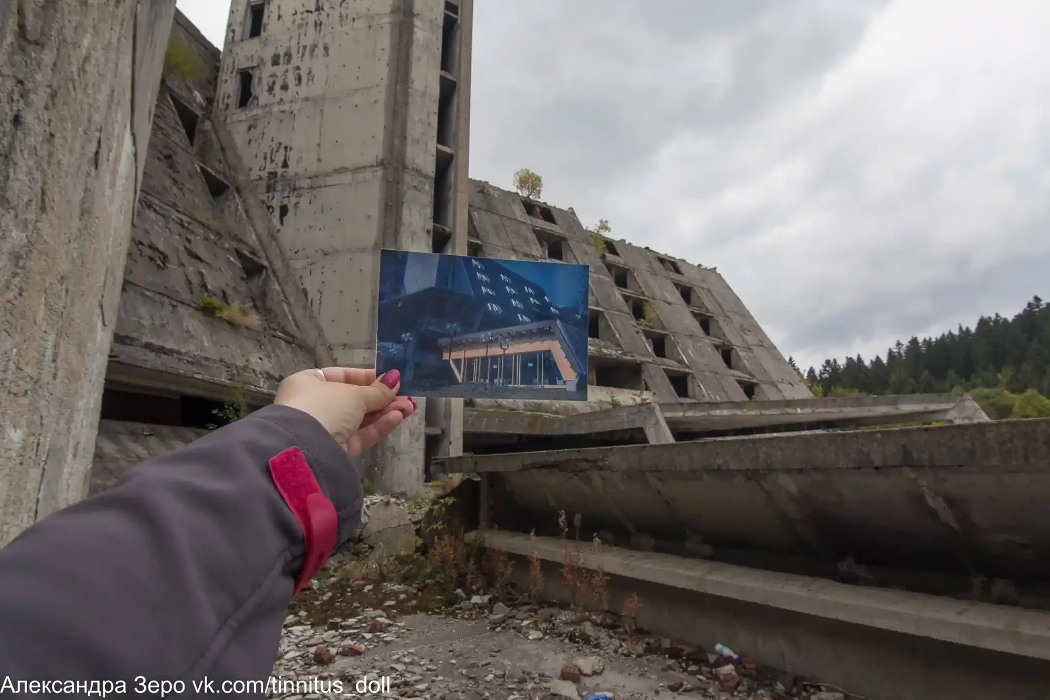 A photograph of the original Hotel Igman held against its modern ruins