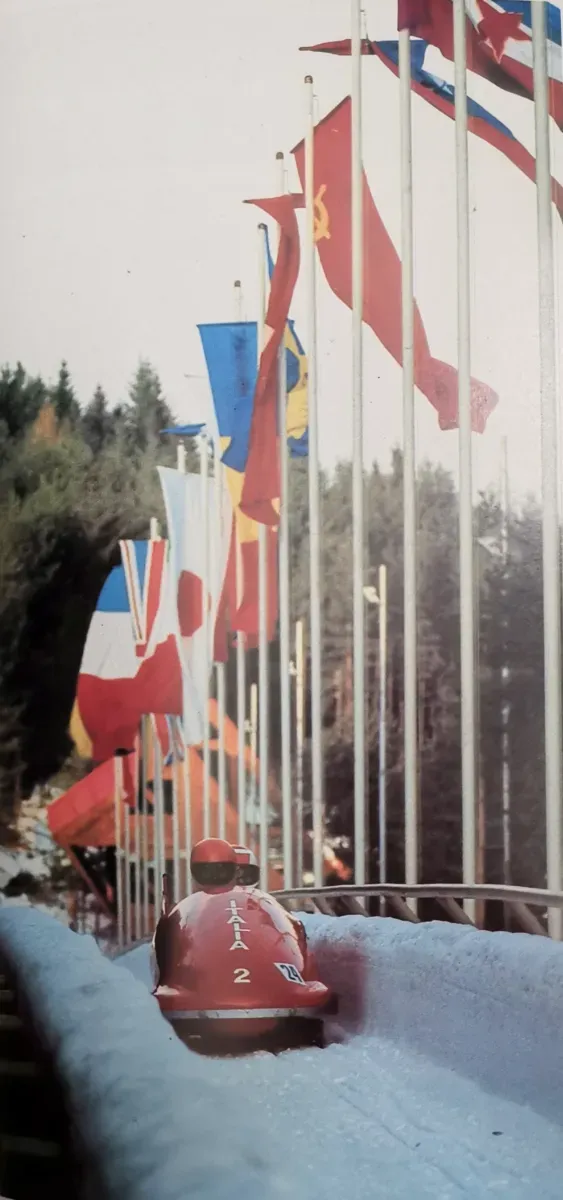 Italian bobsledders race past international flags at Trebević in 1984