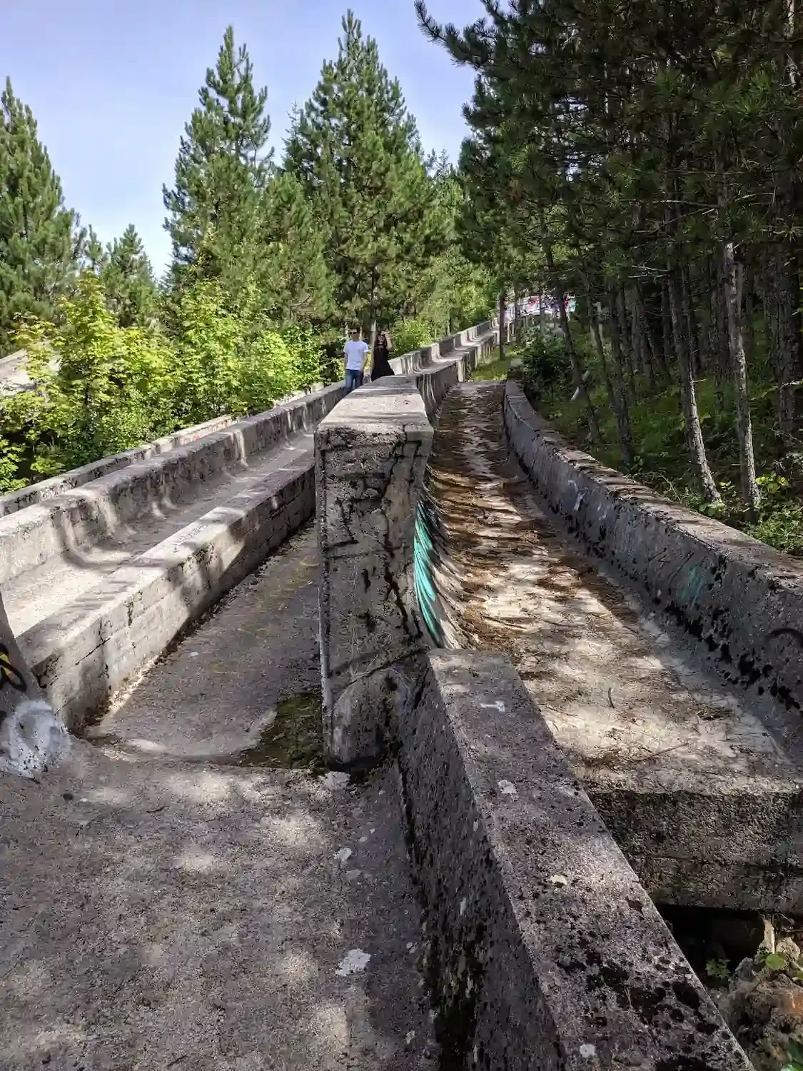 Visitors walk along the Trebević bobsled track switch in 2020